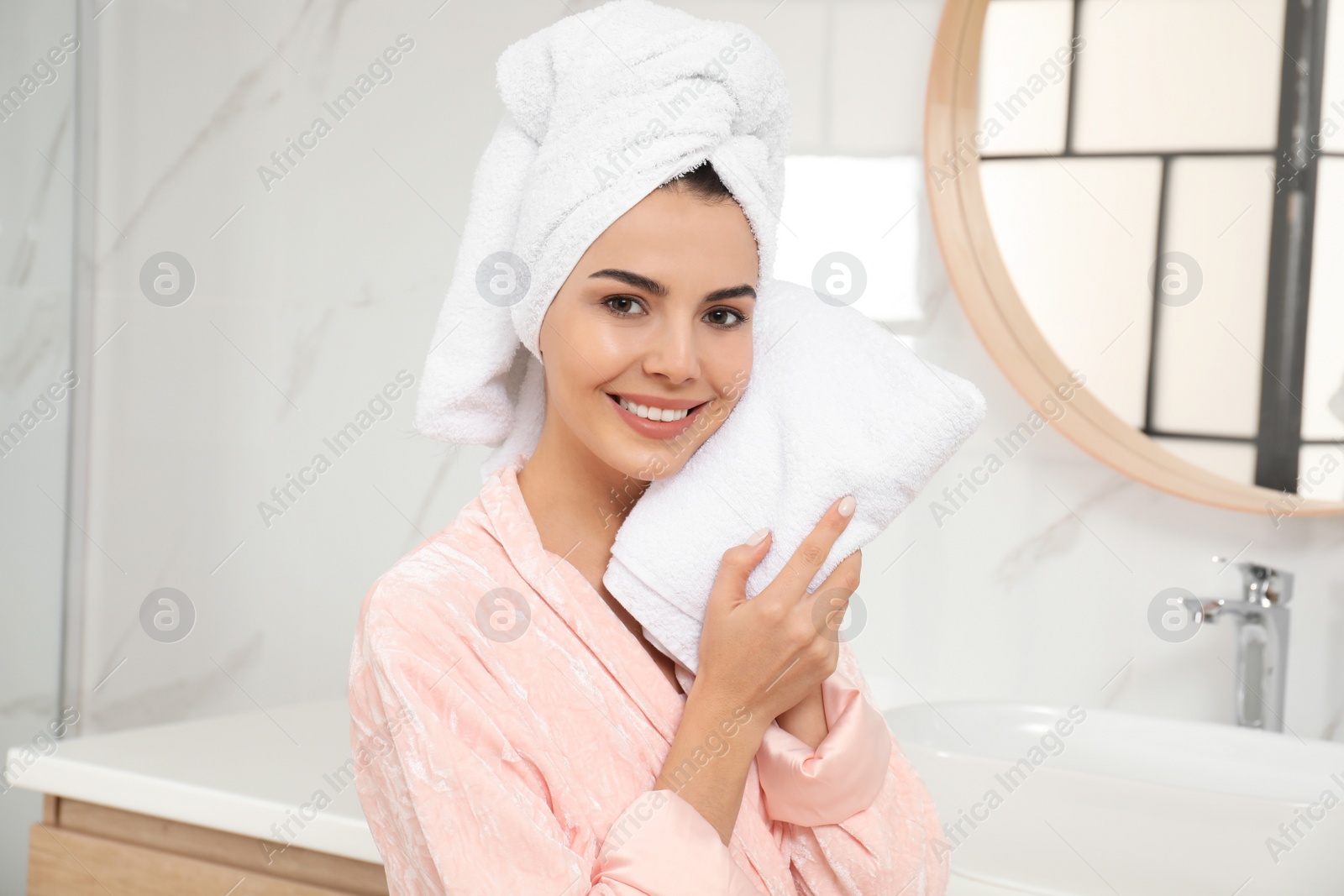 Photo of Young woman wiping face with towel in bathroom