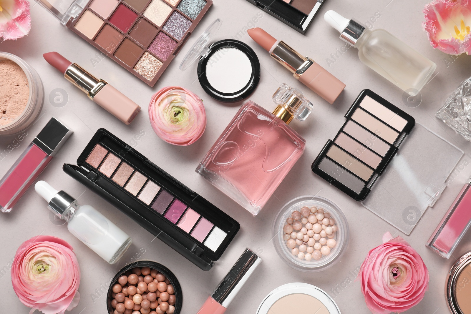 Photo of Flat lay composition with different makeup products and beautiful spring flowers on grey background