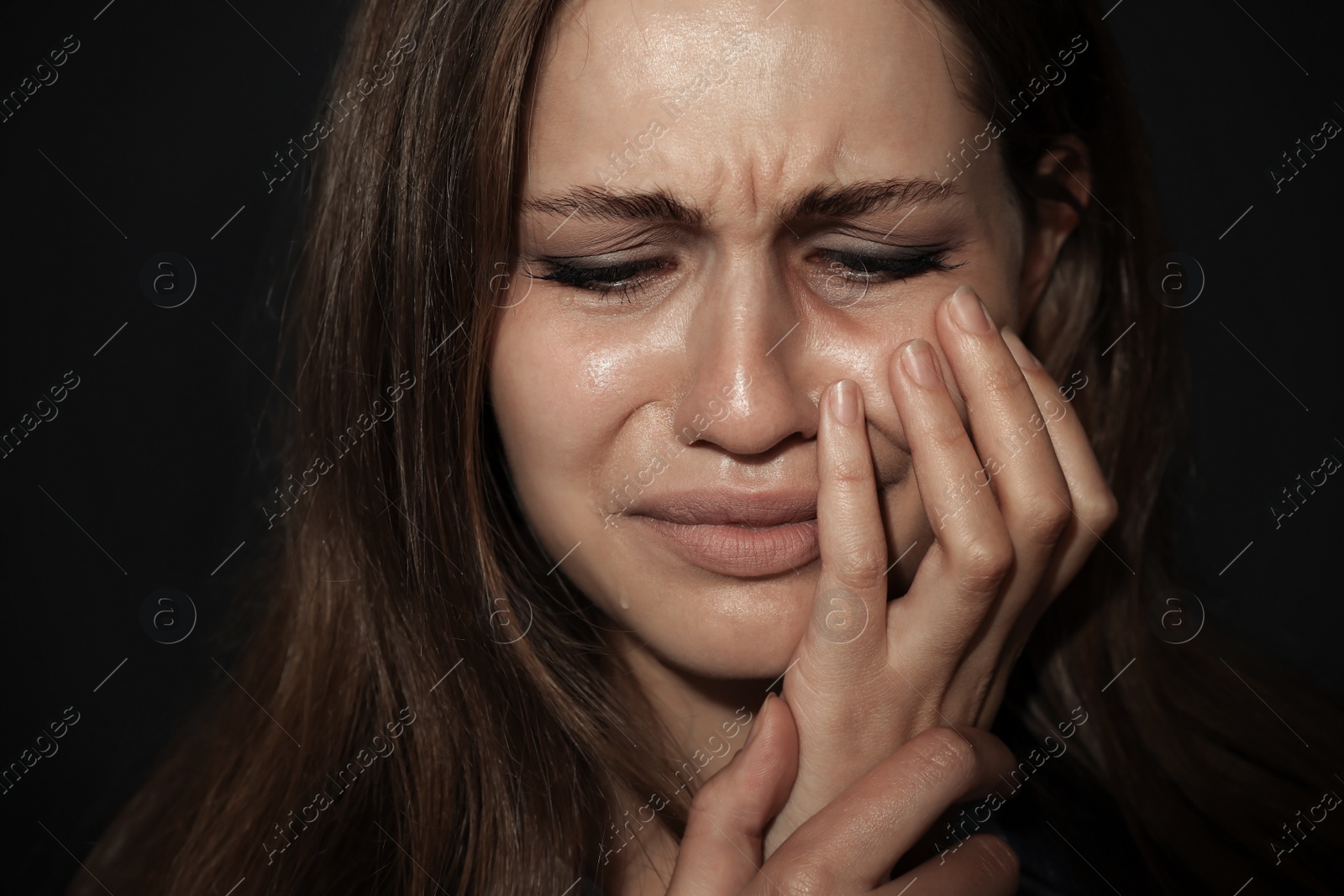 Photo of Crying young woman on dark background. Stop violence