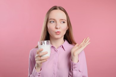 Photo of Cute woman with milk mustache holding glass of tasty dairy drink on pink background
