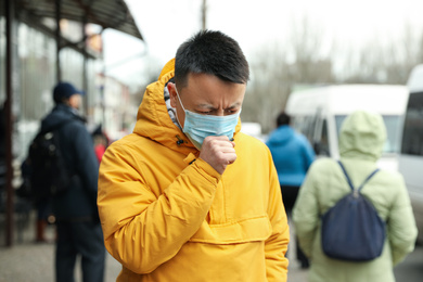 Photo of Asian man wearing medical mask on city street. Virus outbreak