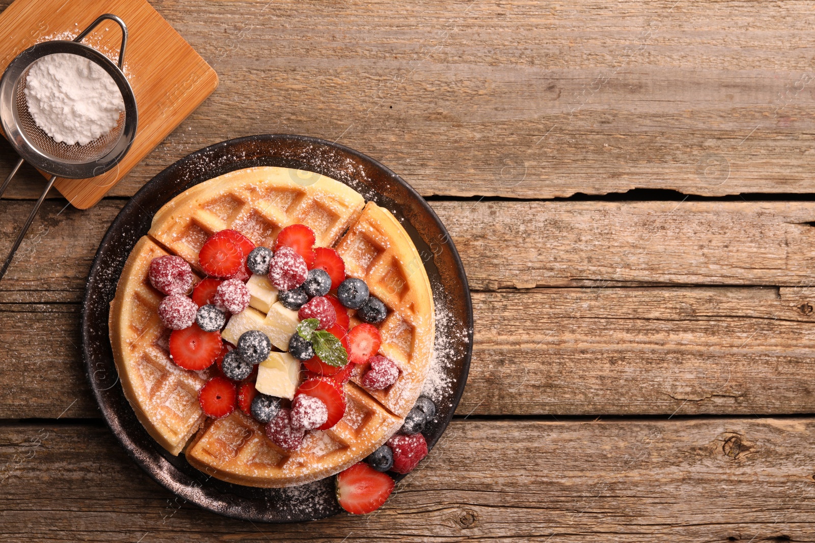 Photo of Tasty Belgian waffle with fresh berries, cheese and powdered sugar on wooden table, flat lay. Space for text
