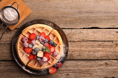 Photo of Tasty Belgian waffle with fresh berries, cheese and powdered sugar on wooden table, flat lay. Space for text