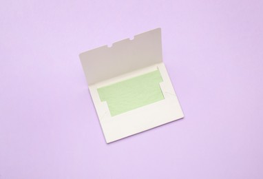 Photo of Facial oil blotting tissues on violet background, top view. Mattifying wipes