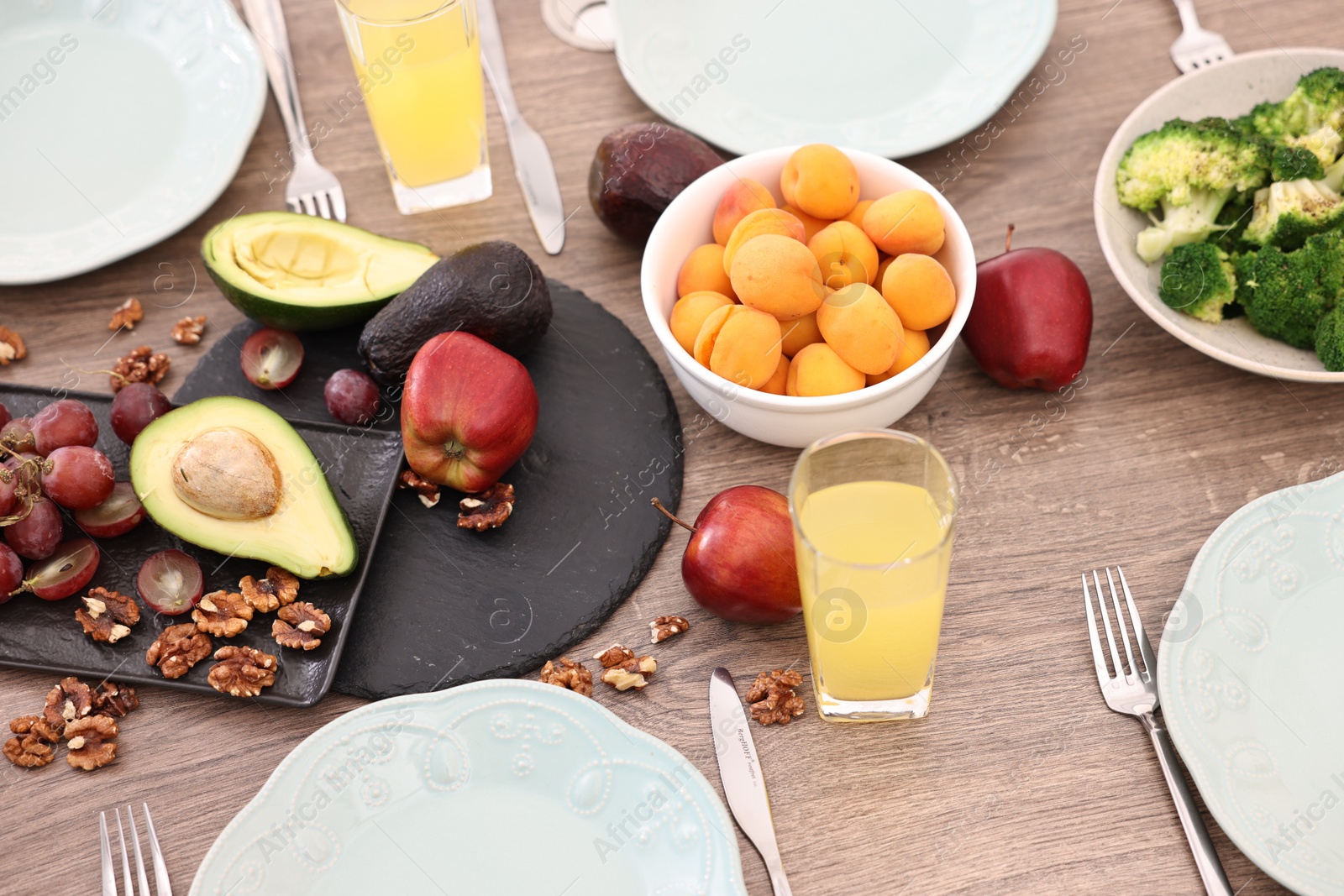 Photo of Healthy vegetarian food, glasses of juice, plates and cutlery on wooden table
