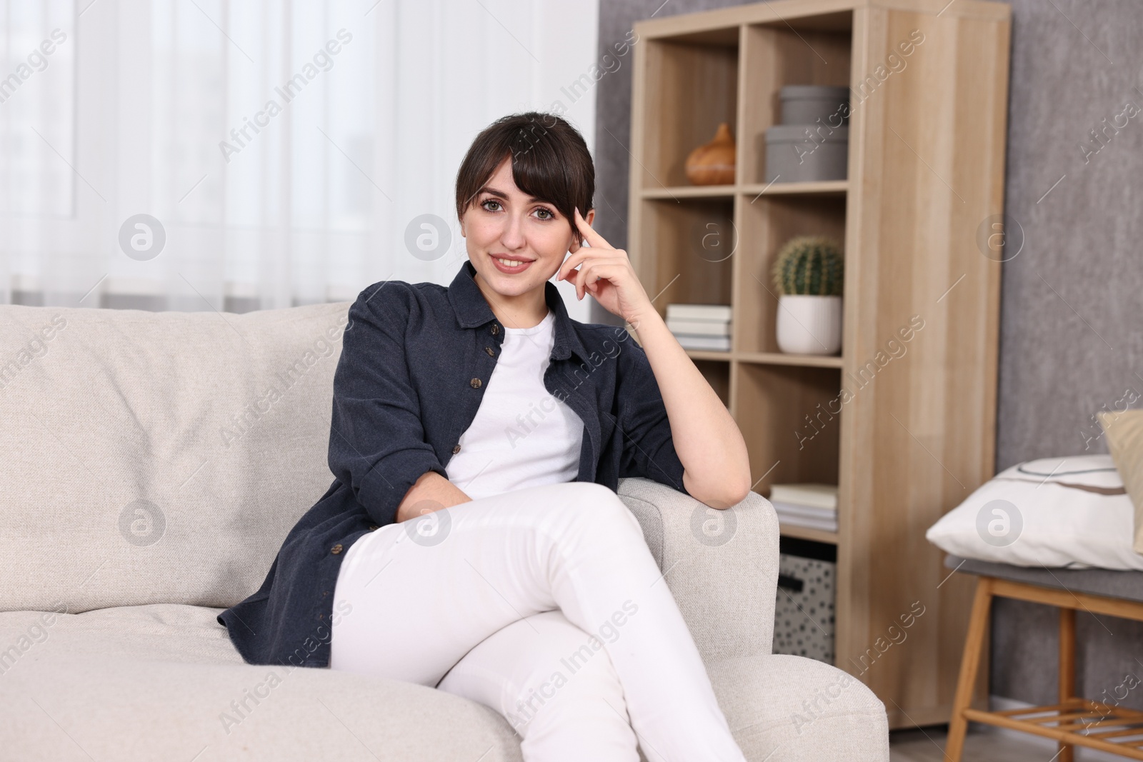 Photo of Beautiful young housewife on sofa at home