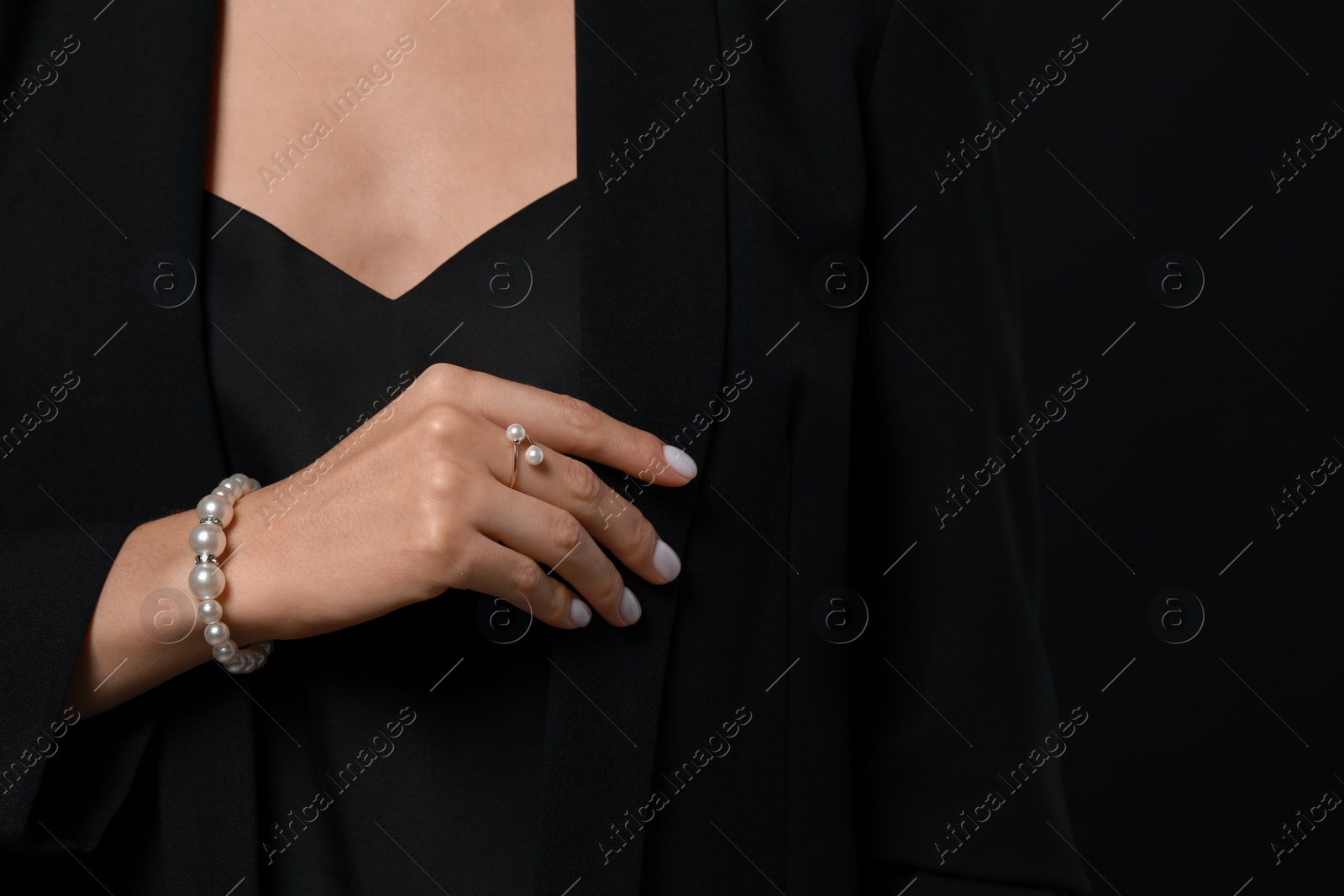 Photo of Young woman with elegant pearl jewelry on black background, closeup