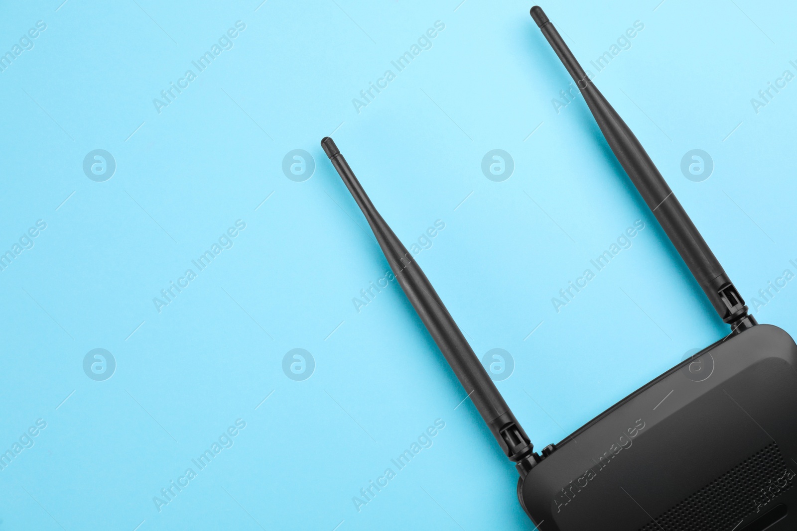 Photo of Modern Wi-Fi router on light blue background, top view. Space for text