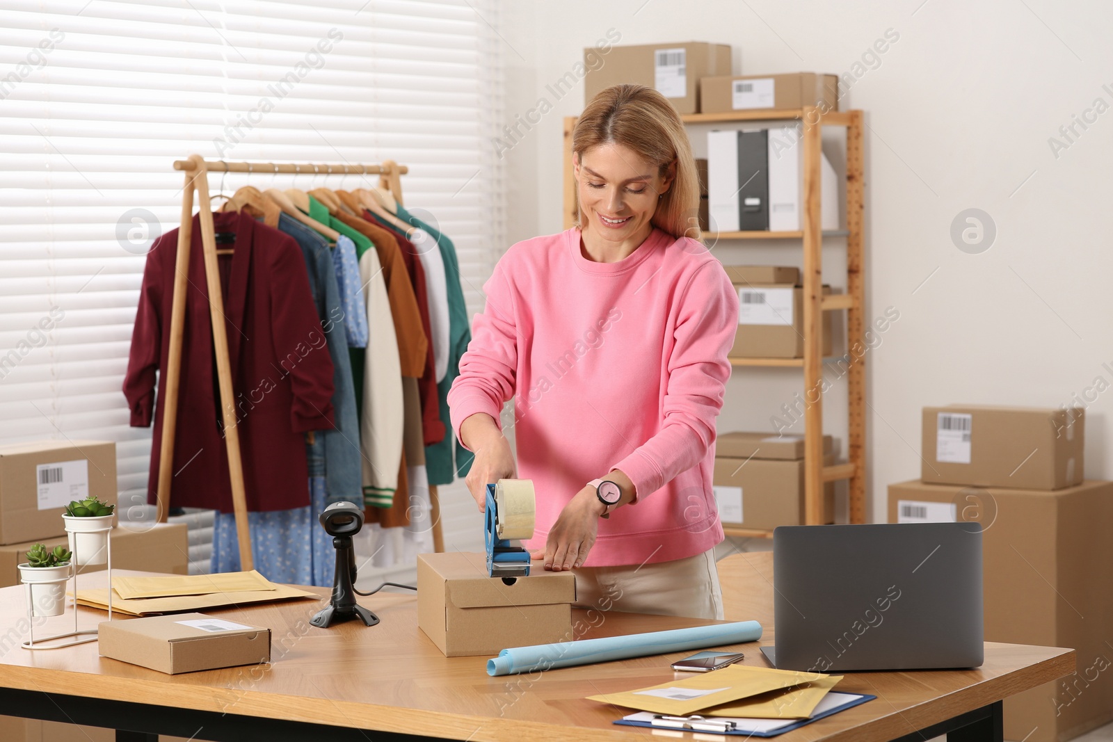 Photo of Seller taping parcel at workplace. Online store