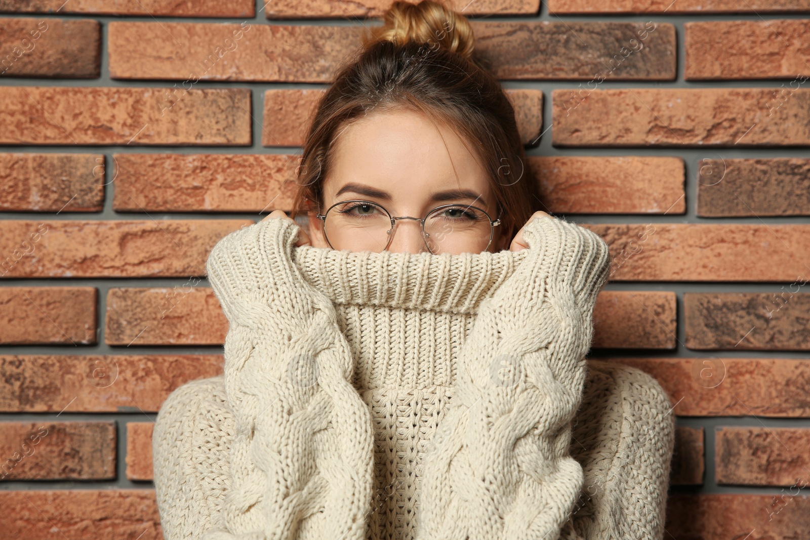 Photo of Beautiful young woman in warm sweater near brick wall