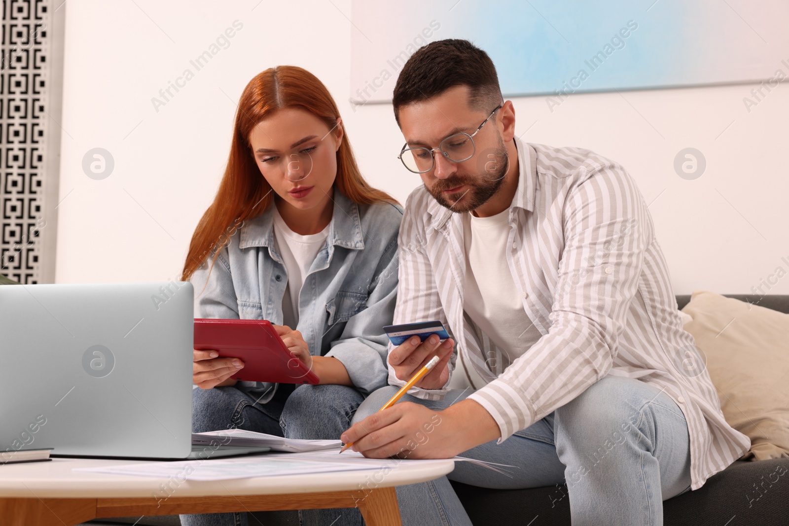 Photo of Couple filling in tax payment form at table in living room