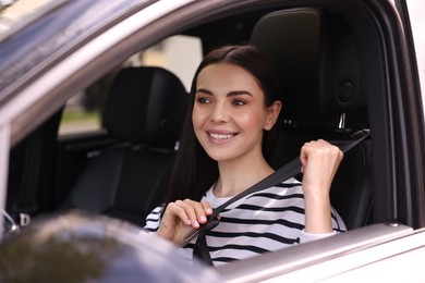 Photo of Woman fastening safety seat belt inside modern car
