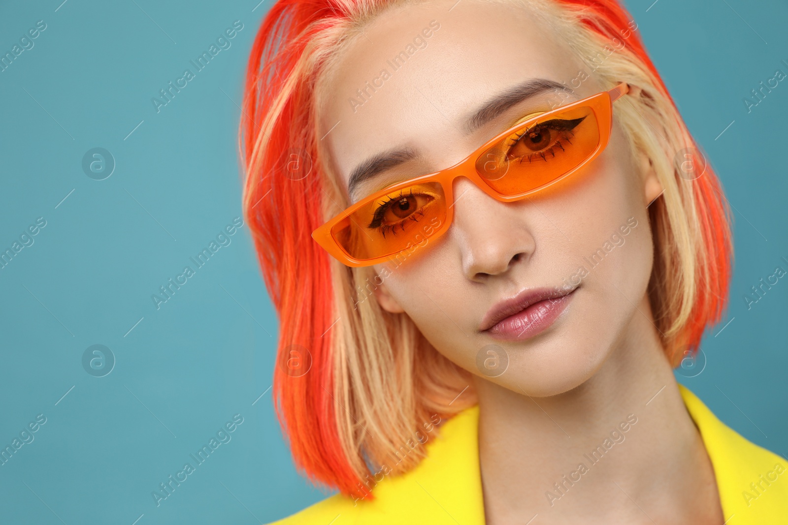 Photo of Beautiful young woman with bright dyed hair on turquoise background, closeup