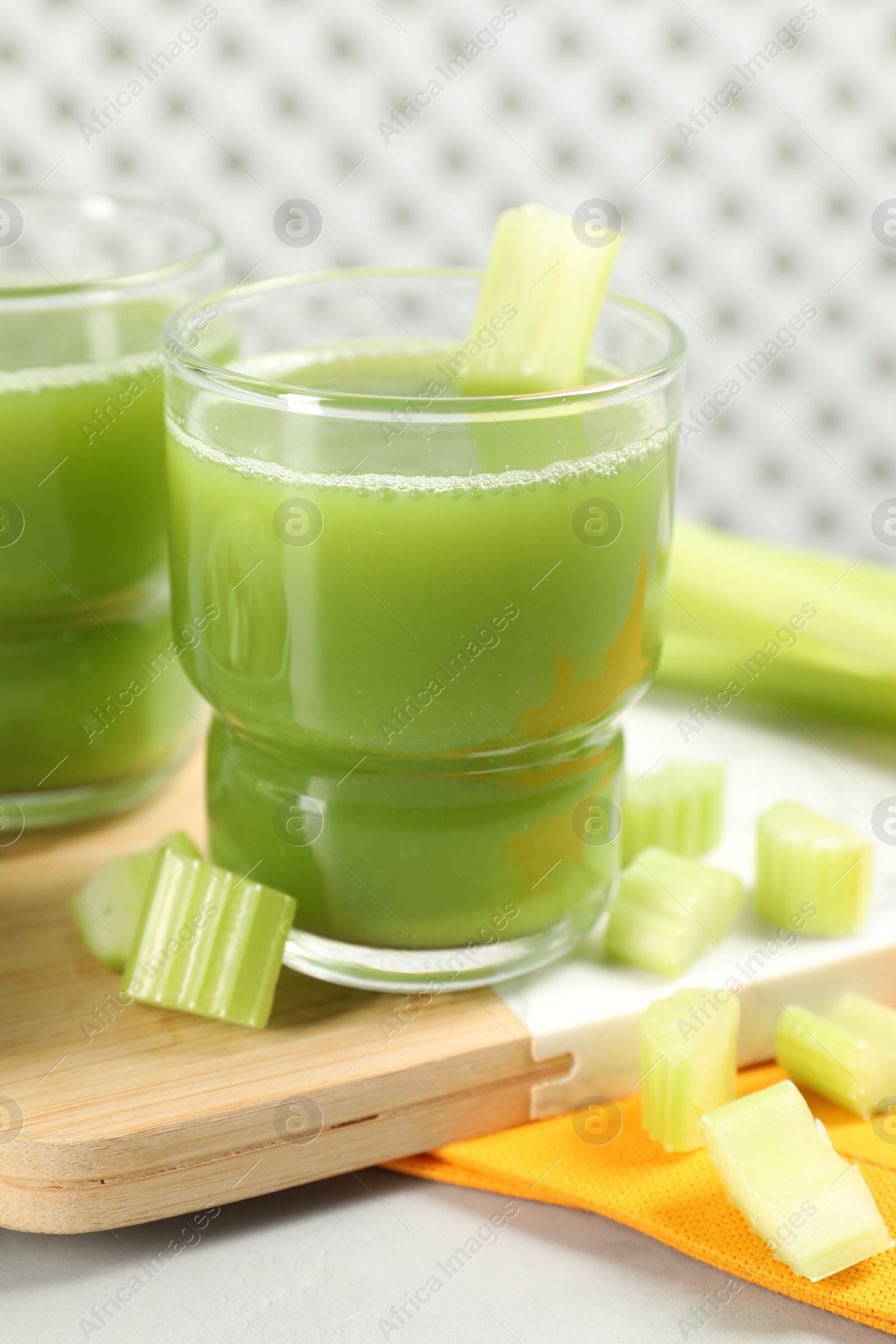 Photo of Celery juice and fresh vegetables on light gray table, closeup