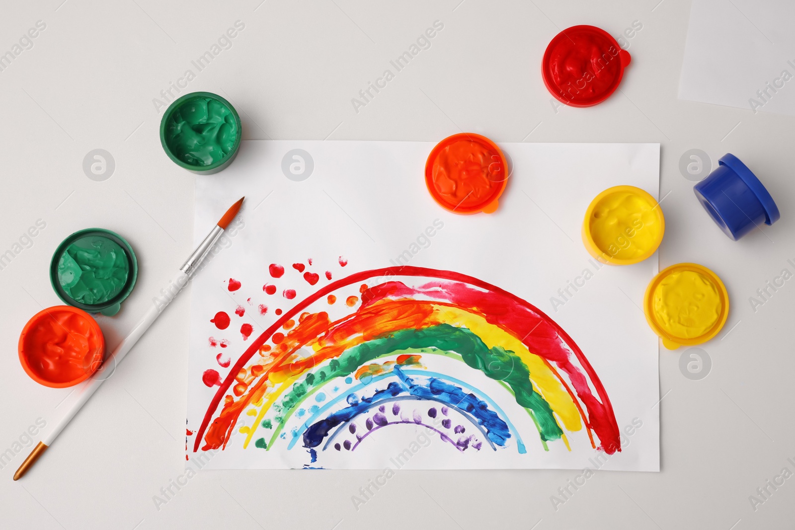 Photo of Cute children drawing, brush and set of paints on white table, flat lay