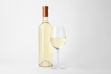 Photo of Bottle and glass of expensive white wine on light background