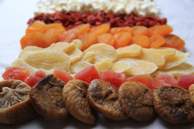 Different tasty dried fruits on paper, closeup