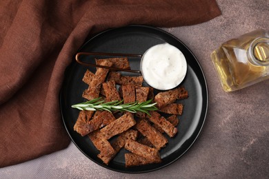 Photo of Crispy rusks with rosemary and sauce on grey table, flat lay
