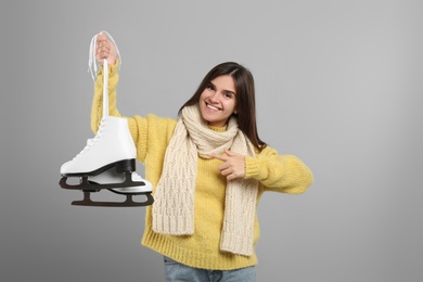 Photo of Happy woman with ice skates on grey background