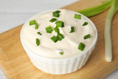 Photo of Fresh sour cream with onion on wooden board, closeup