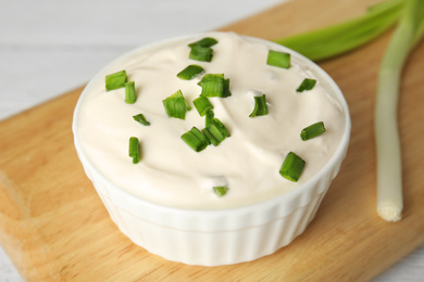 Fresh sour cream with onion on wooden board, closeup