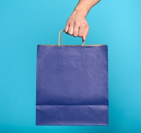 Photo of Young man with paper bag on blue background, closeup