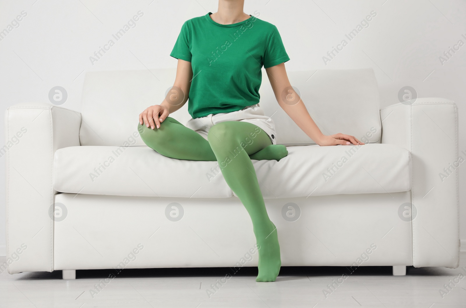 Photo of Woman wearing green tights sitting on sofa indoors, closeup