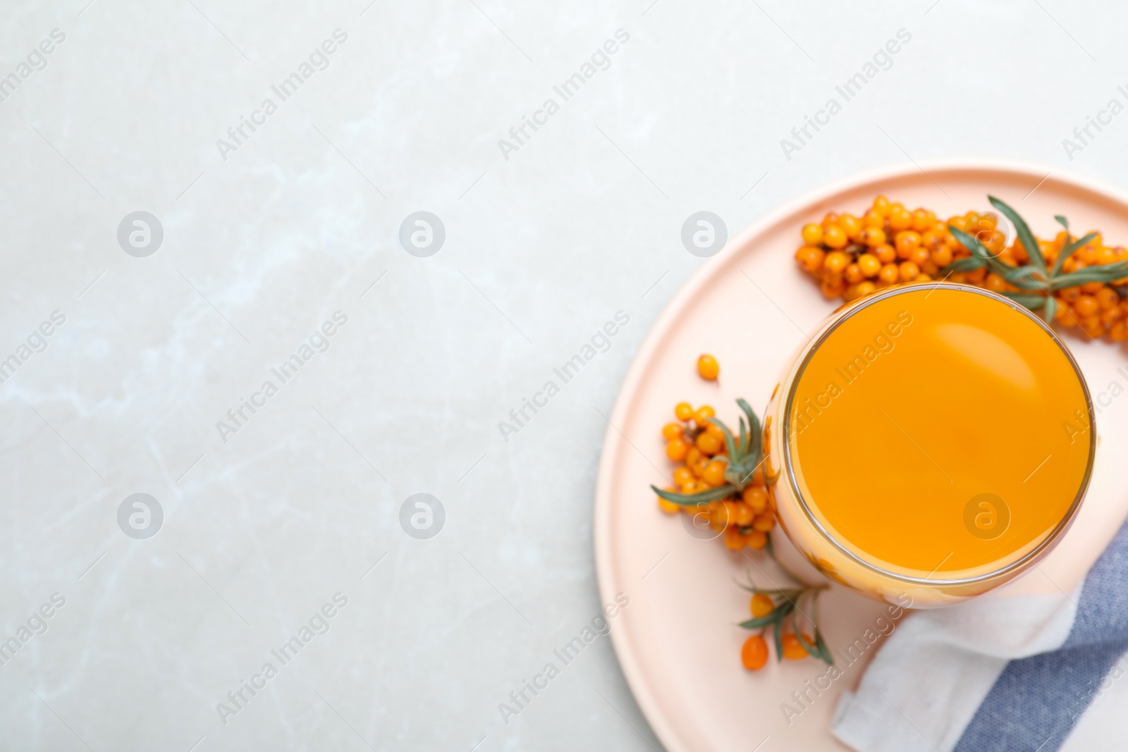 Photo of Delicious sea buckthorn juice and fresh berries on light grey marble table, top view. Space for text