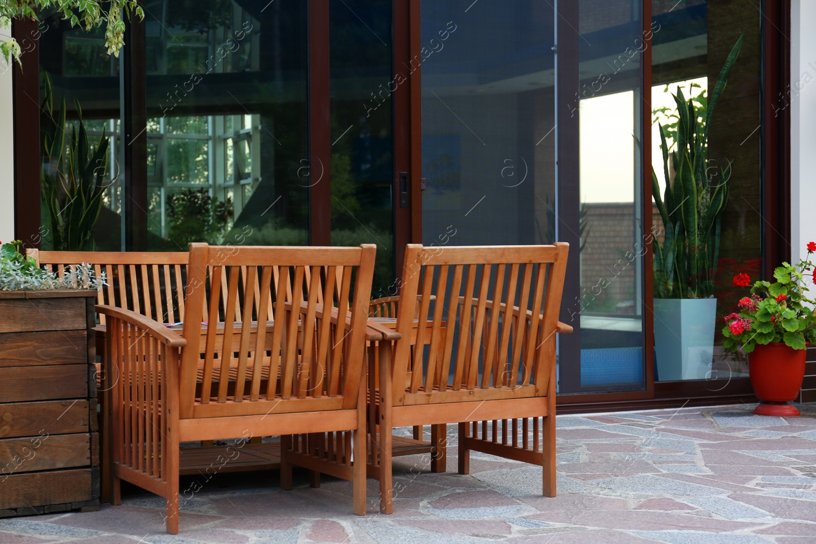 Photo of Wooden garden furniture on backyard near modern house