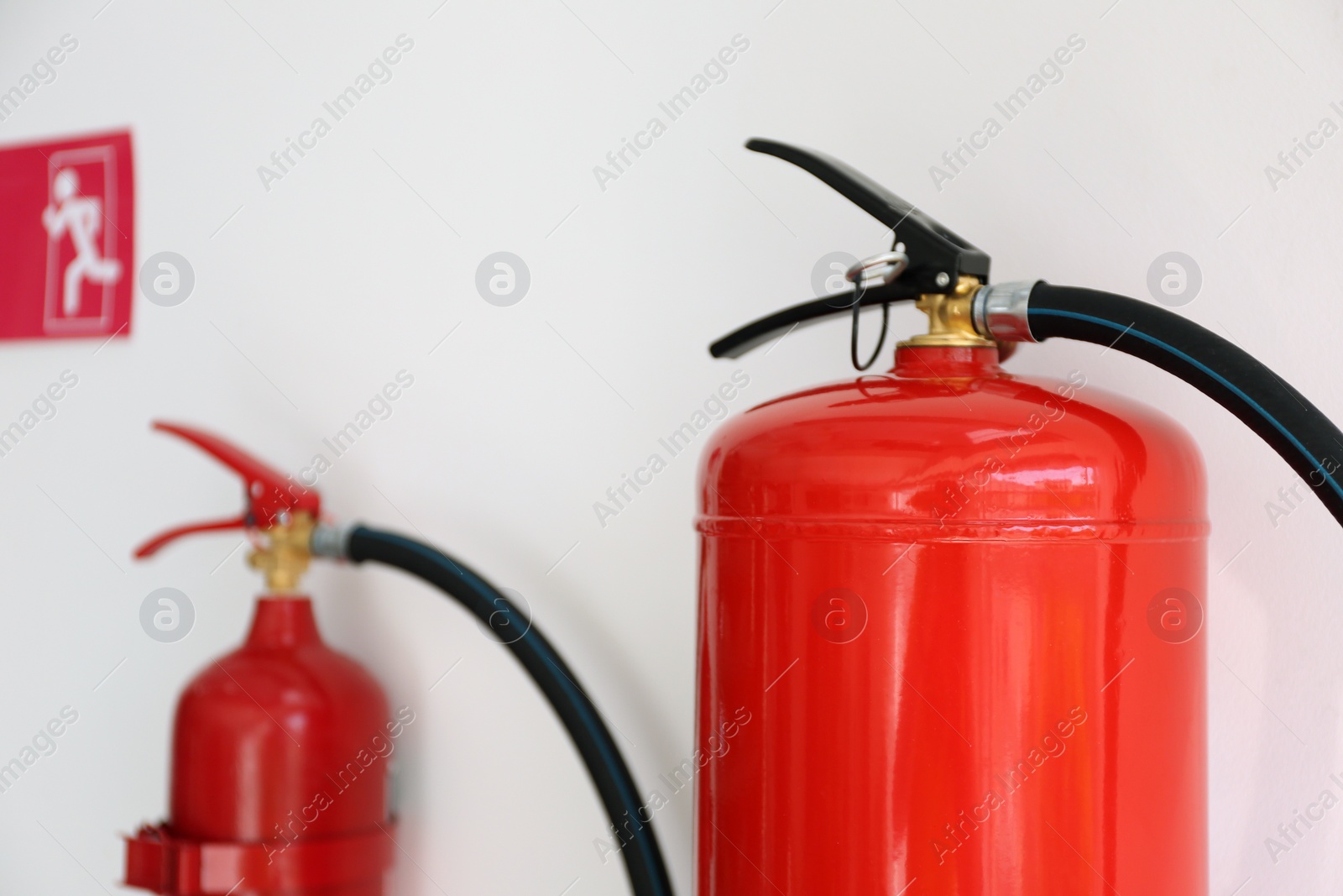 Photo of Fire extinguishers hanging on white wall, closeup