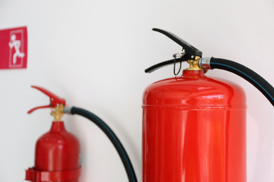 Photo of Fire extinguishers hanging on white wall, closeup