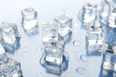 Melting ice cubes and water drops on light background, closeup