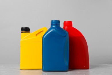 Photo of Motor oil in different canisters on grey marble table against light background