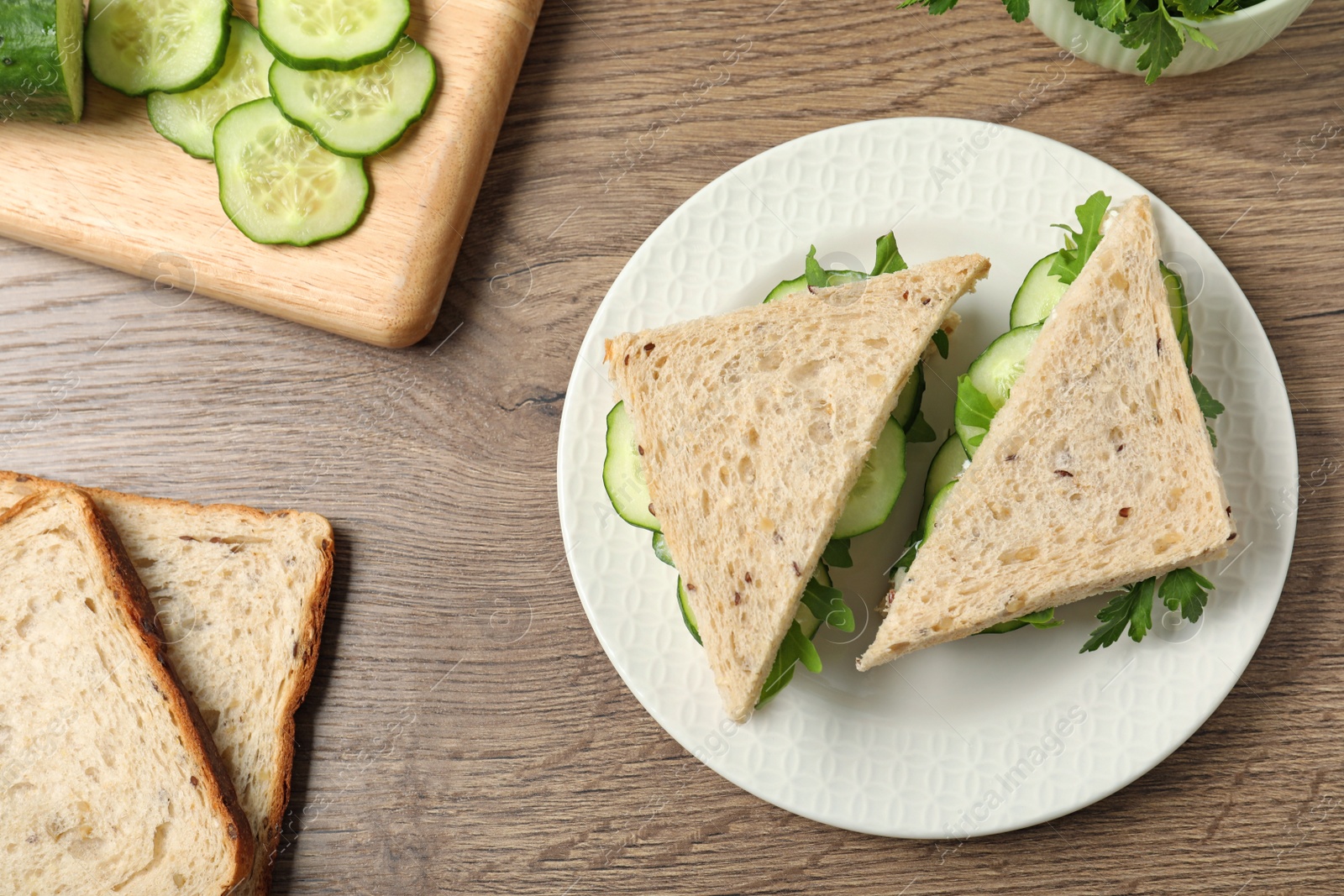 Photo of Flat lay composition with traditional English cucumber sandwiches and ingredients on wooden background