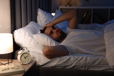 Photo of Frustrated man suffering from insomnia on bed