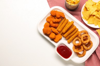 Tasty ketchup and different snacks on white table, flat lay. Space for text