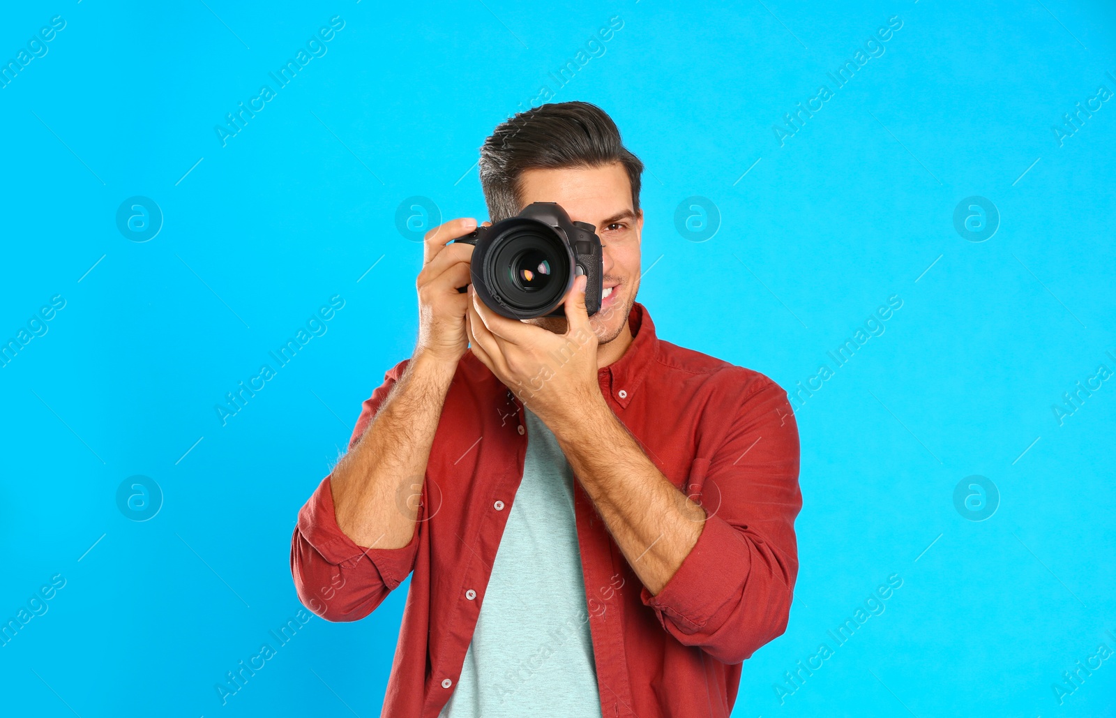 Photo of Professional photographer working on light blue background in studio