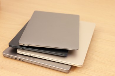 Different modern laptops on wooden table, closeup