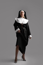 Woman in nun habit and mesh tights on grey background. Sexy costume
