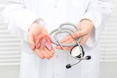 Endocrinologist holding stethoscope and model of thyroid gland, closeup