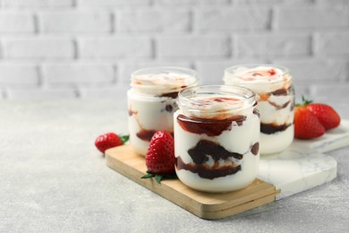 Tasty yoghurt with jam and strawberries on grey table, closeup