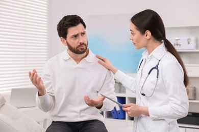 Photo of Doctor with tablet consulting patient during appointment in clinic