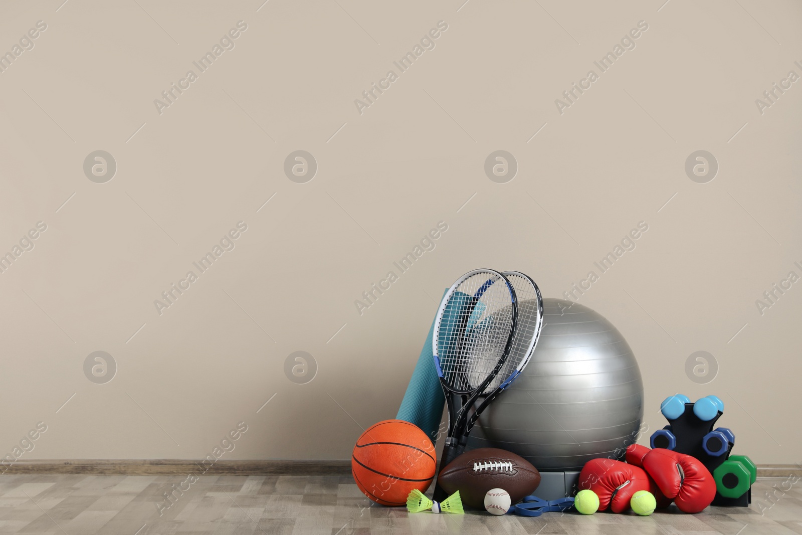 Photo of Set of different sports equipment on floor near beige wall, space for text