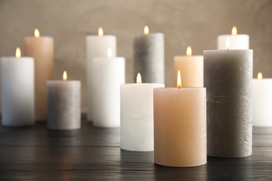 Photo of Burning candles on table against color background. Space for text