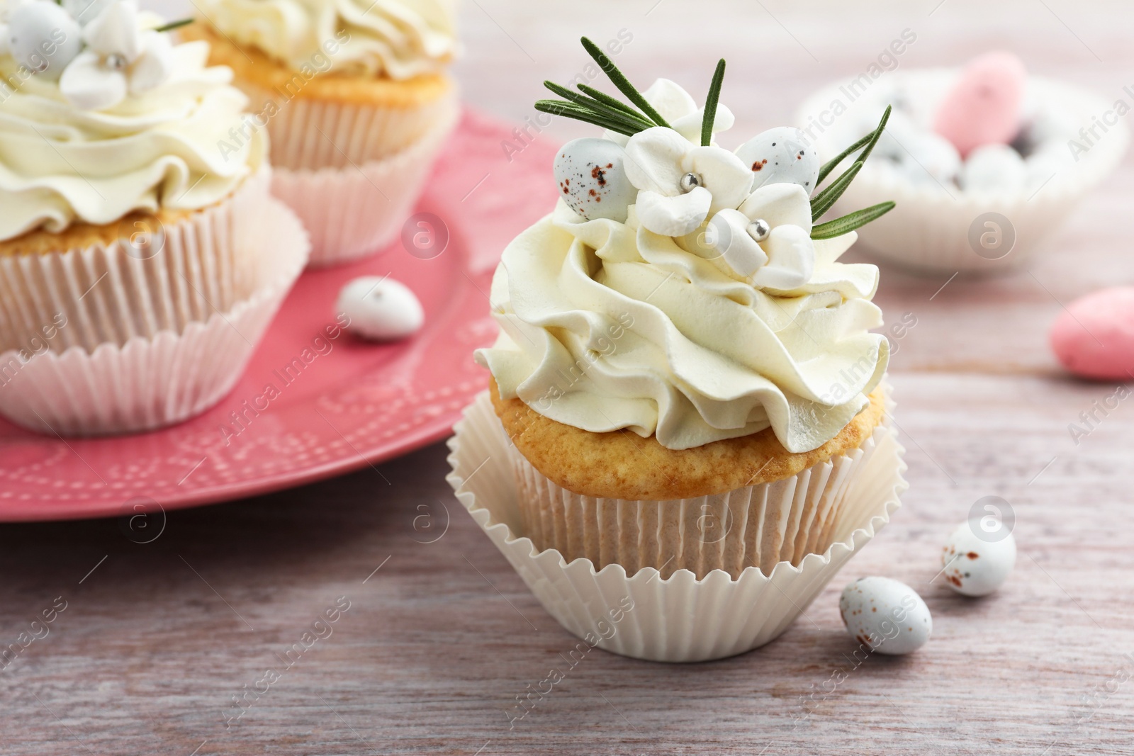 Photo of Tasty Easter cupcakes with vanilla cream on wooden table, closeup