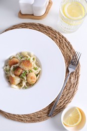 Delicious scallop pasta with spices in bowl served on white table, flat lay