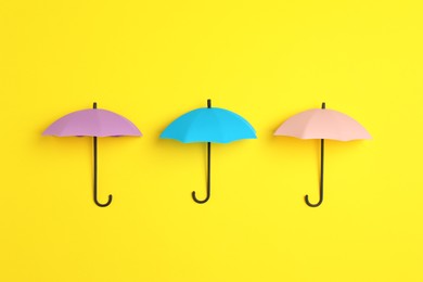 Photo of Bright toy umbrellas on yellow background, flat lay