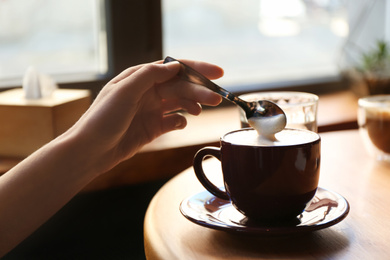 Photo of Woman with aromatic coffee at table in cafe, closeup