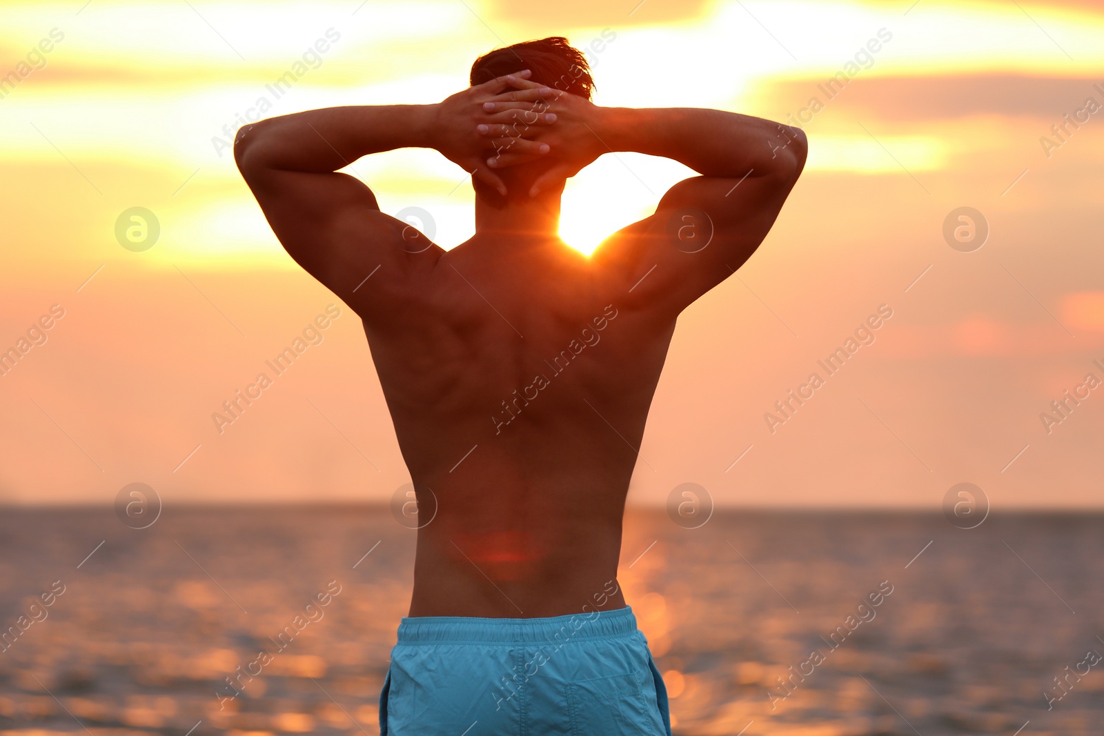 Photo of Handsome young man posing on beach near sea at sunset