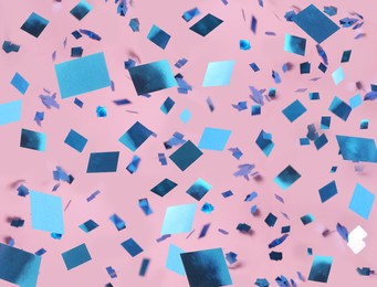 Shiny blue confetti falling down on pink background